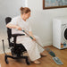 Person mopping the floors at home while sitting in a VELA Activity Chair