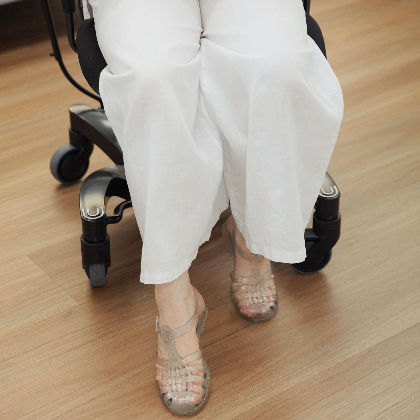 Person walking a VELA Activity Chair with their feet in the space in front of the four wheel base