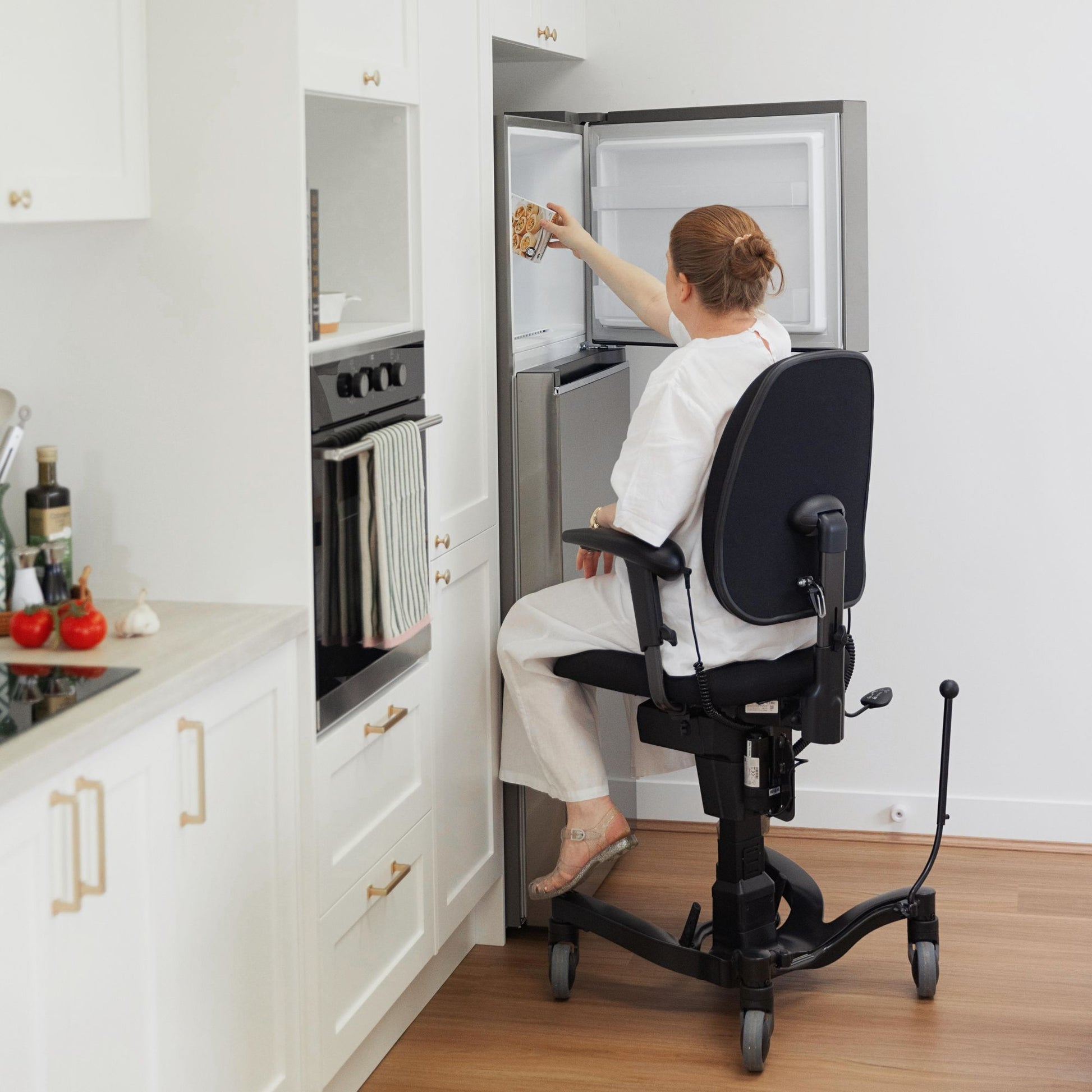 Person at height in a VELA Activity Chair easily reaching into a freezer to get ingredients out to cook a meal