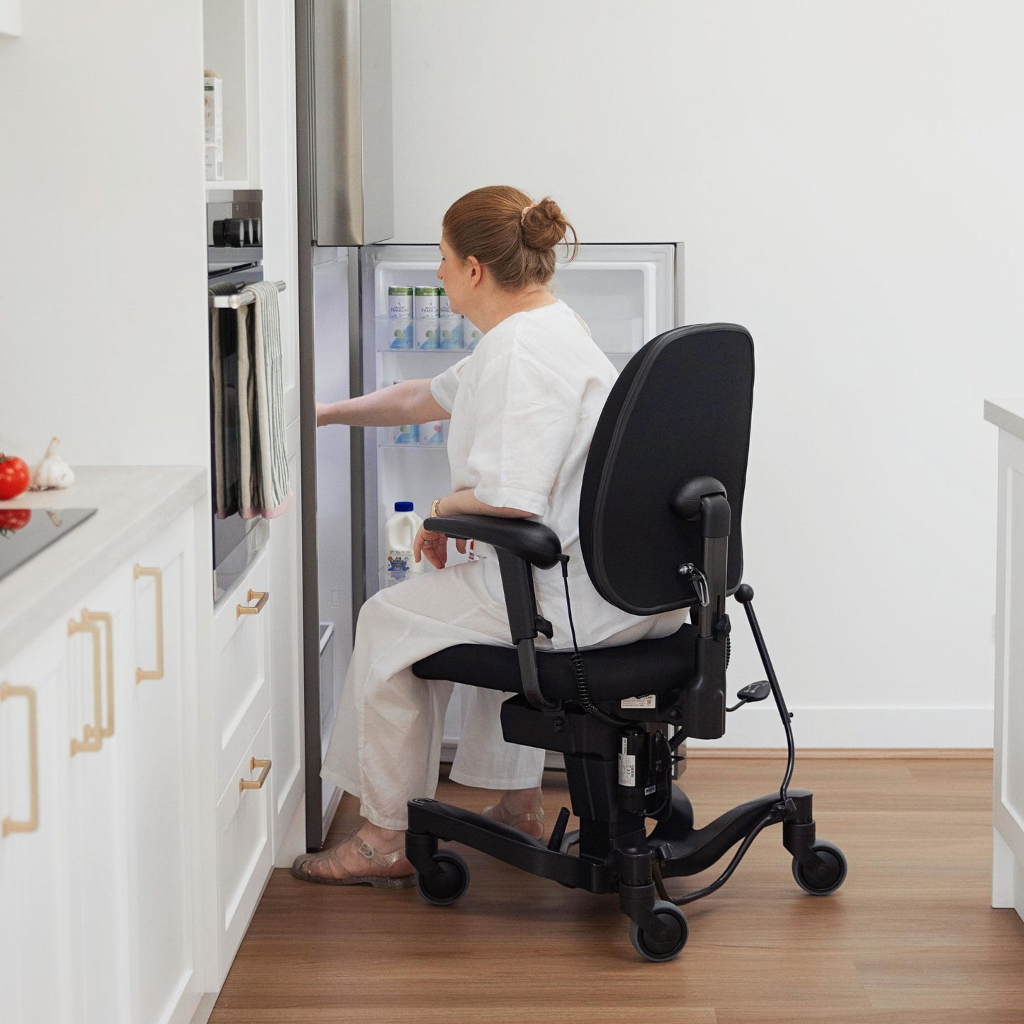Person reaching into a fridge while sitting in a VELA 700E Activity Chair