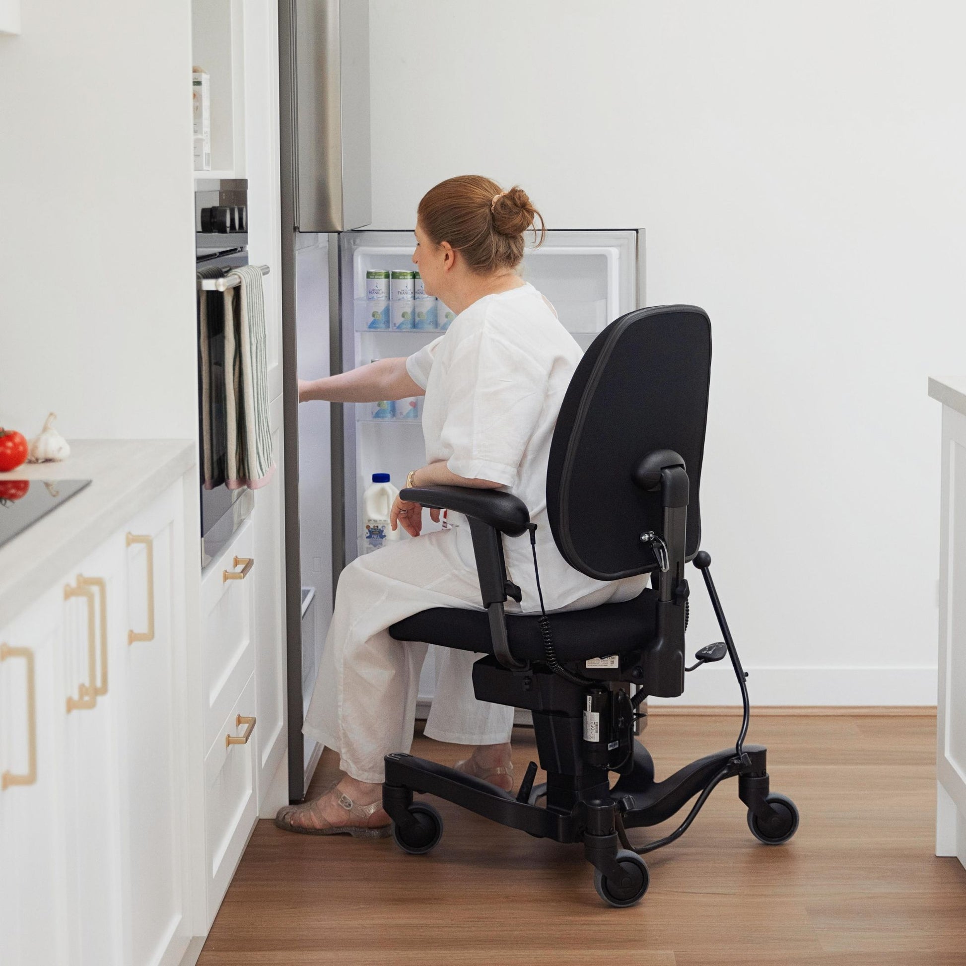 Person reaching into a fridge while sitting in a VELA 700E Activity Chair