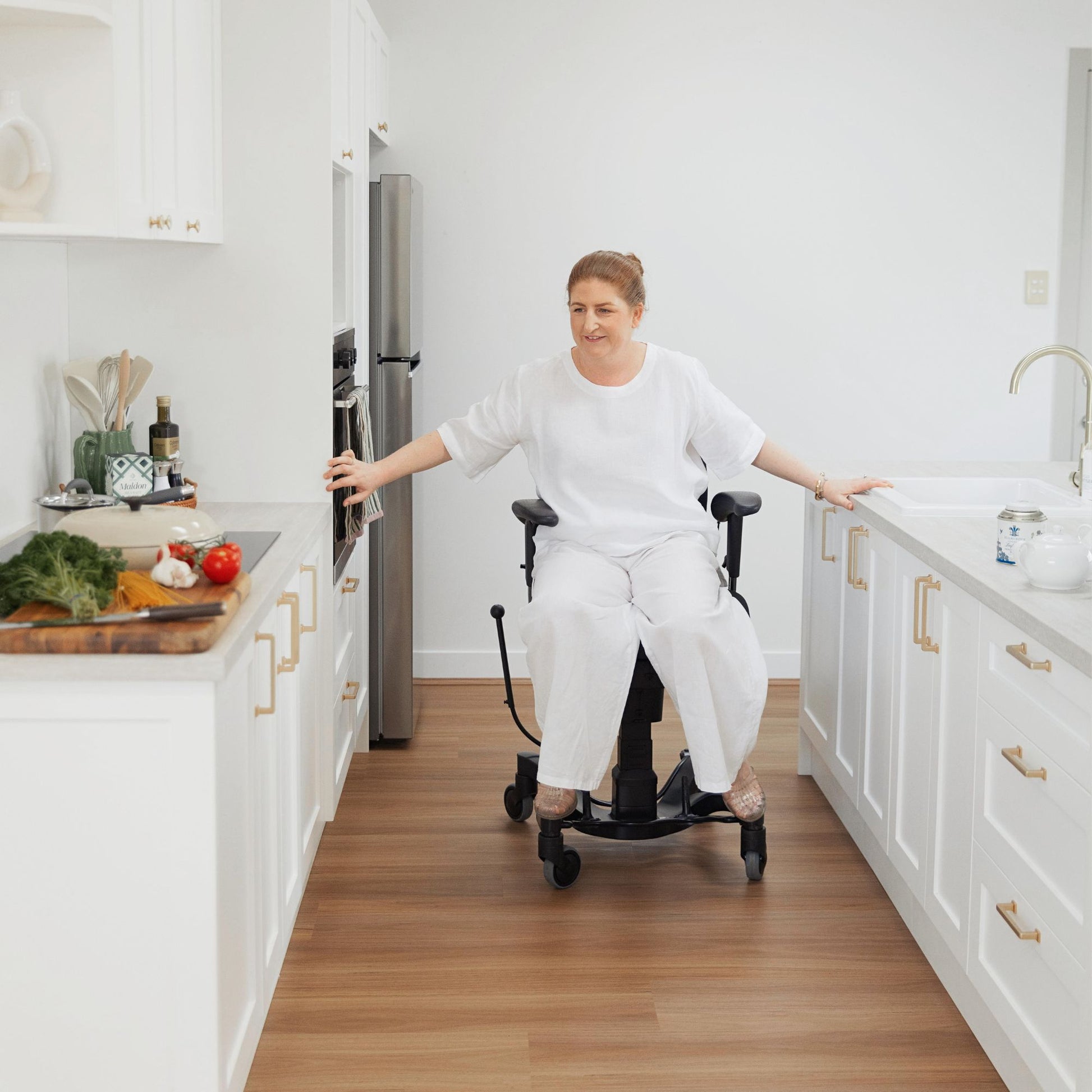 Person using their arms to move the VELA Activity Chair smoothly around the different areas of the kitchen while cooking a meal