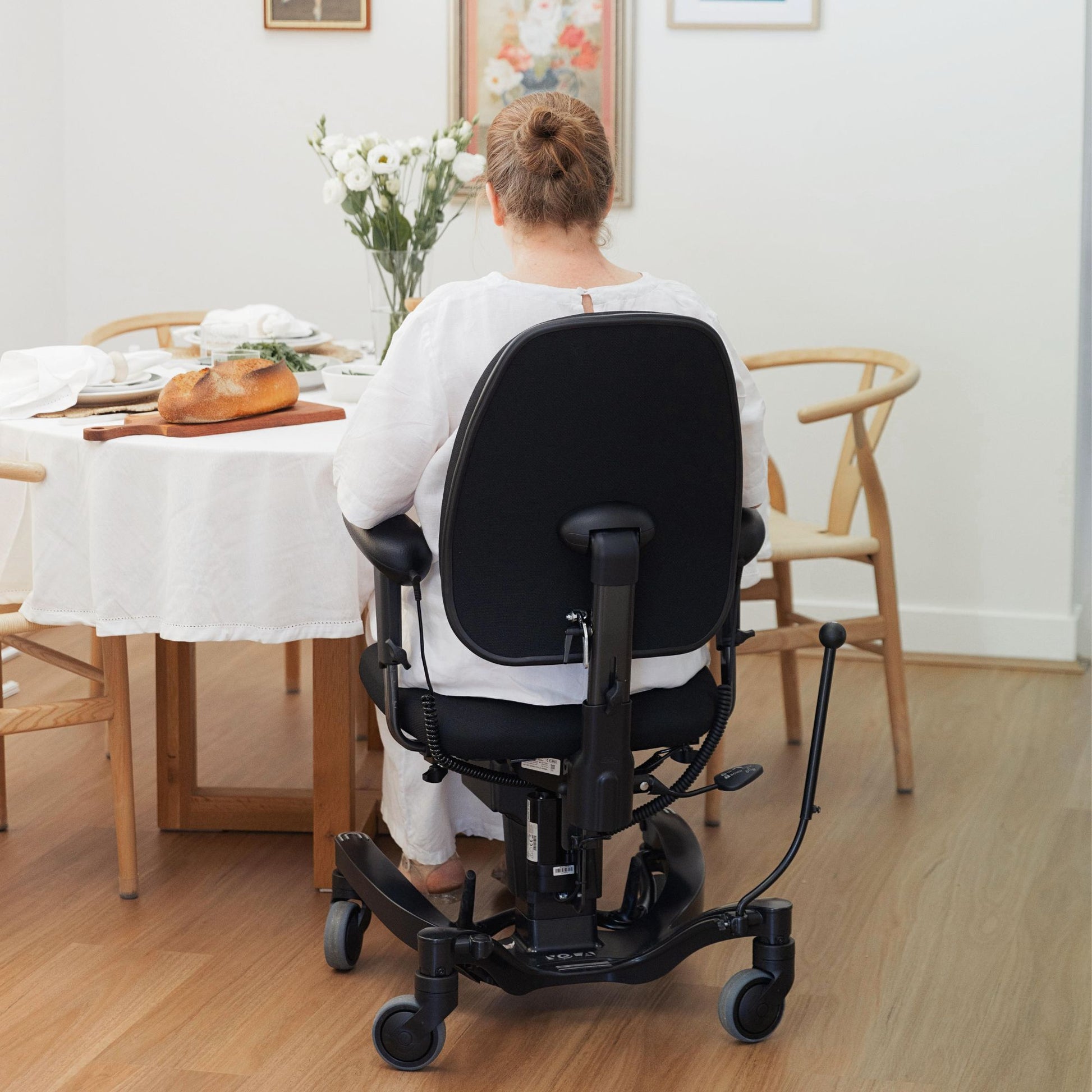 Person seated at the dining table in their VELA Activity Chair which fits under table heights